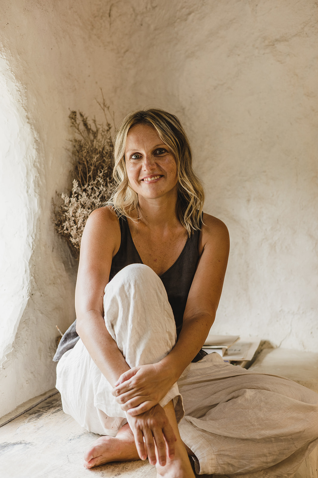 Mara, warm and grounded against a soft plaster wall